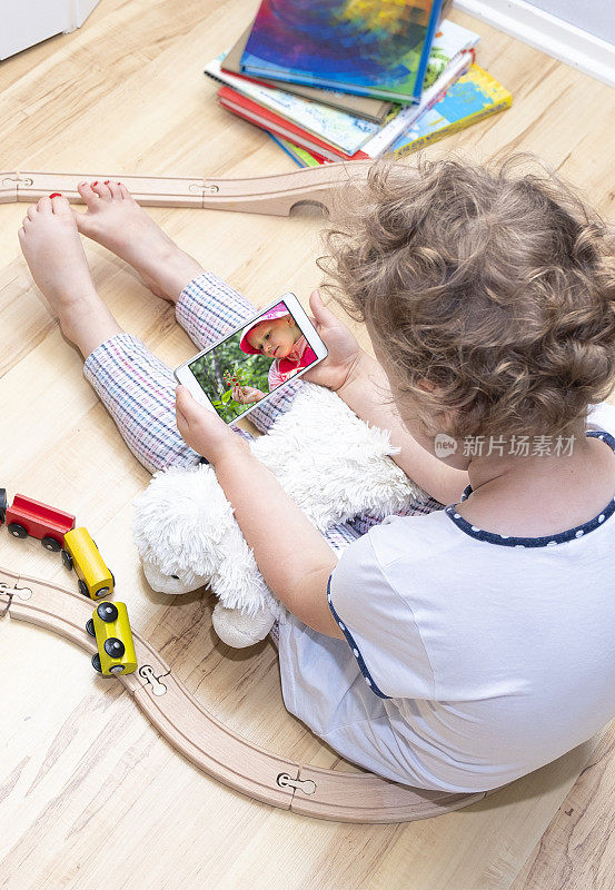 Caucasian girl of 6 years old, sits on the floor and talks on video communication on a mobile phone. Conversation with a friend.